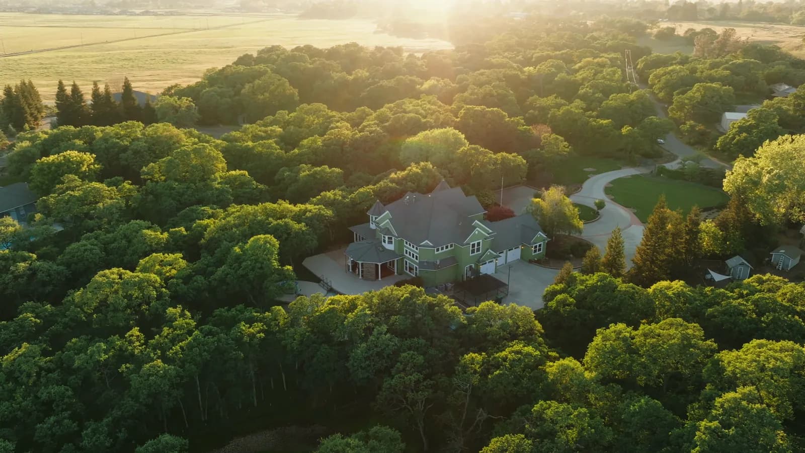 An aerial montage: gardens and a gated drive, a tile-roofed estate and its pool, a white clapboard house with horses on the lawn, and open coastline.