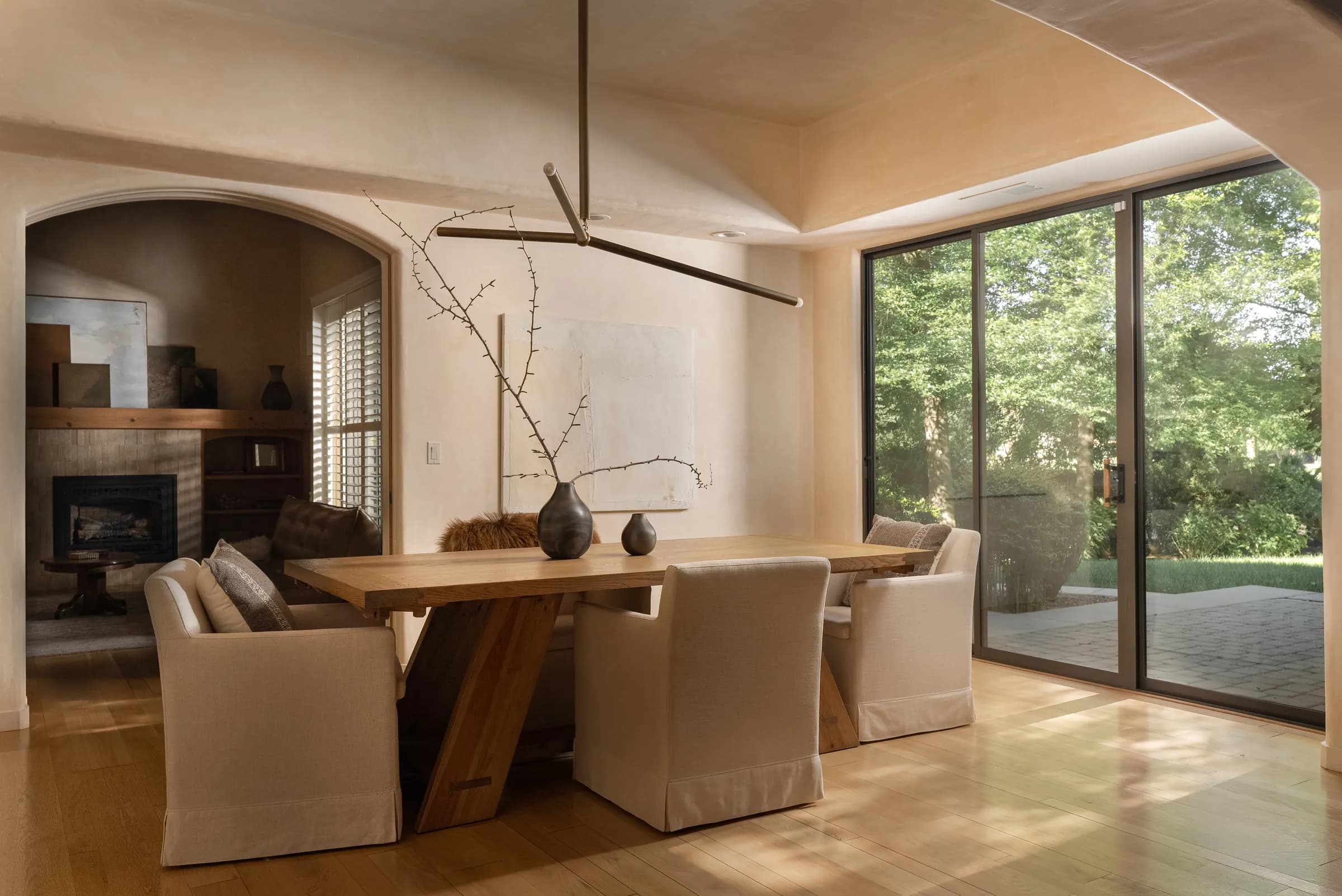 A dining room against a full-height window, the garden held outside and the room lit to match it.