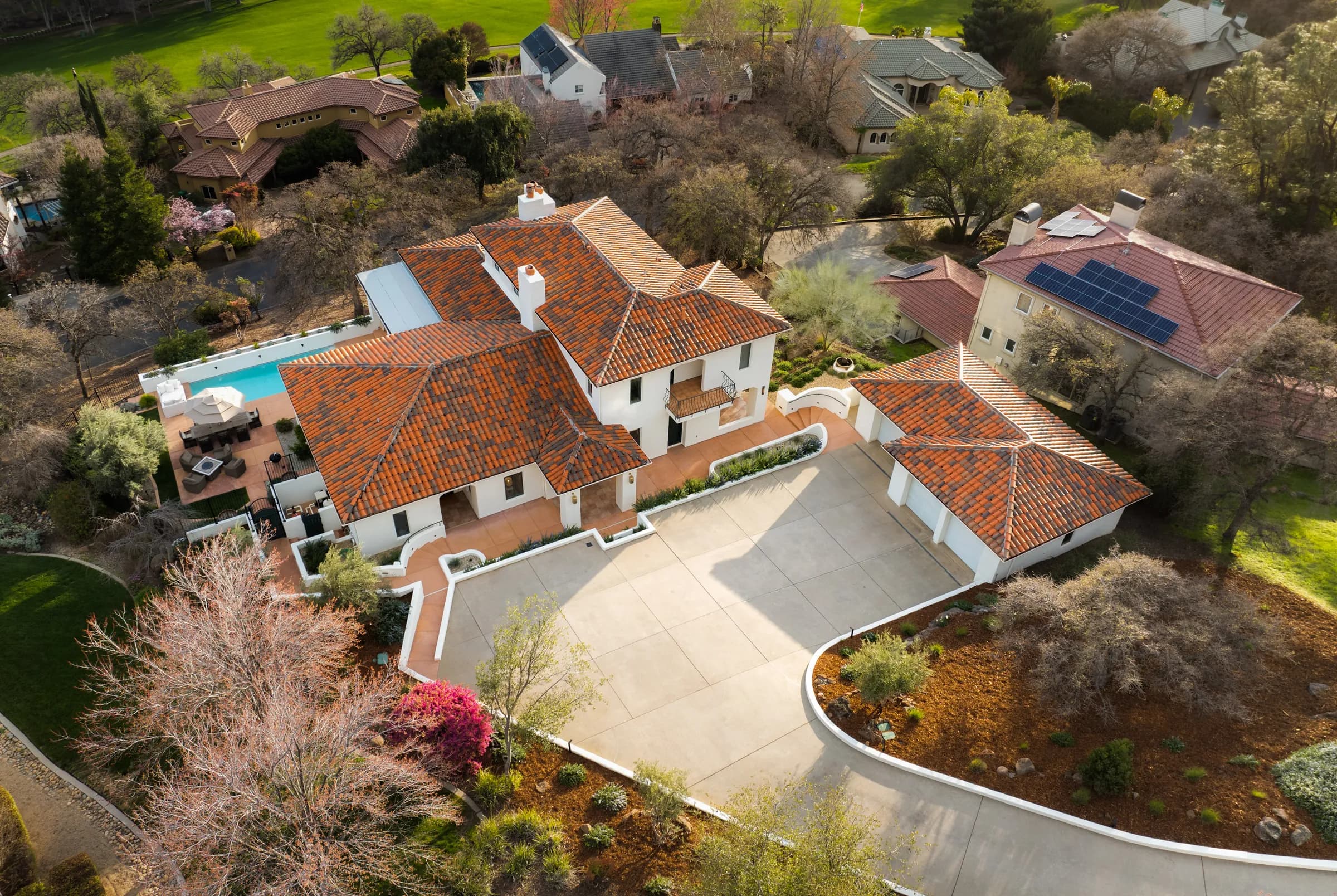A tile-roofed estate from above, its drive curling in through mature planting.