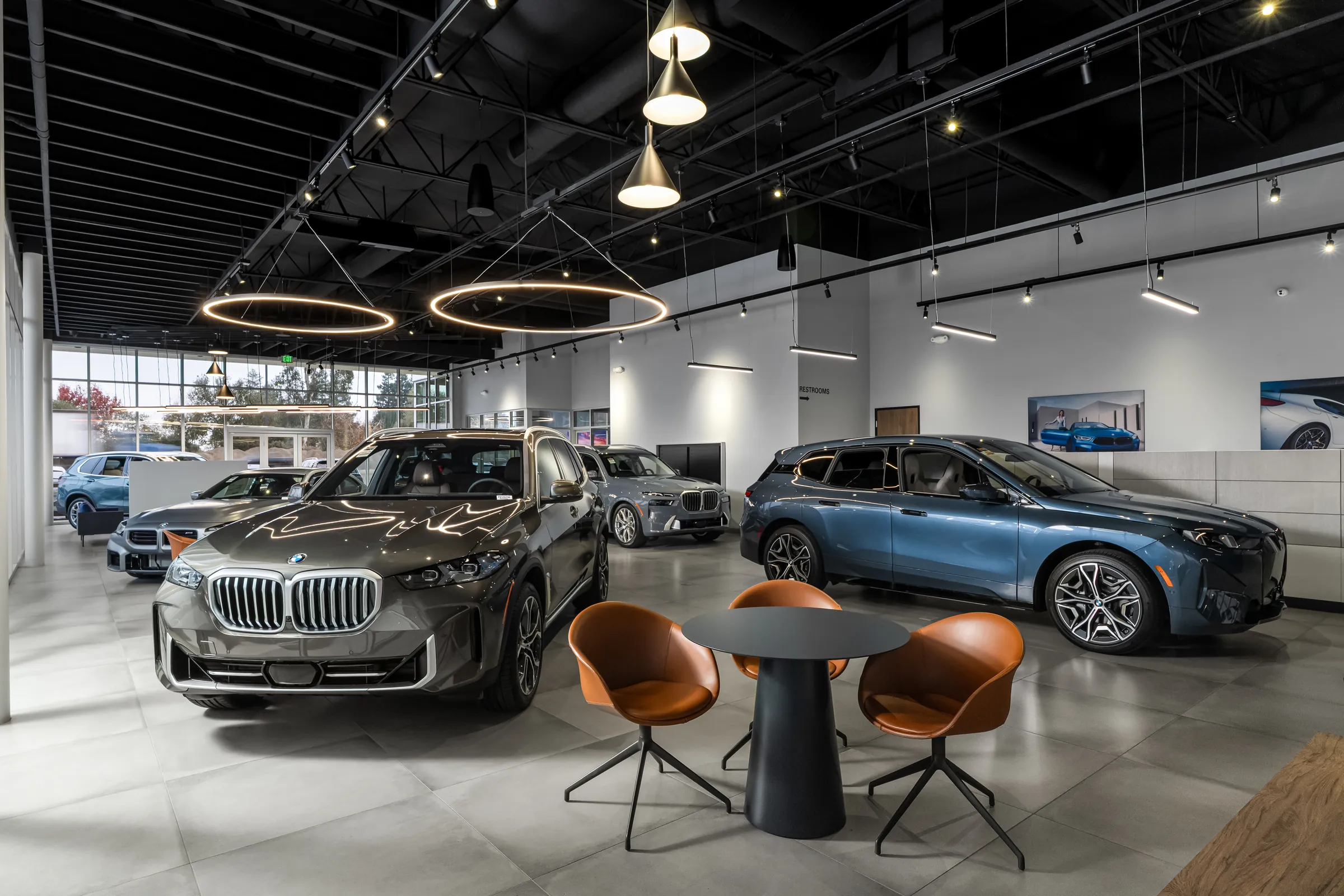 Automotive dealership exteriors at dusk and the showroom interiors behind them. Frame 5 of 6.